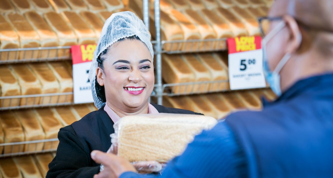 A baker giving a customer a loaf of bread.