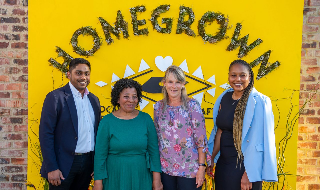 A group of people standing in front of a yellow homegrown back-drop