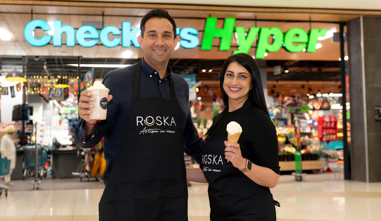 A male and female wearing black aprons holding ice creams